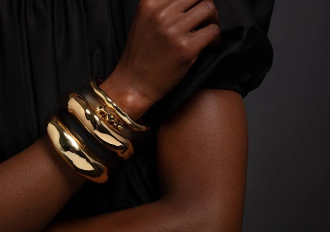 woman wearing a black shirt and three melted gold bracelets