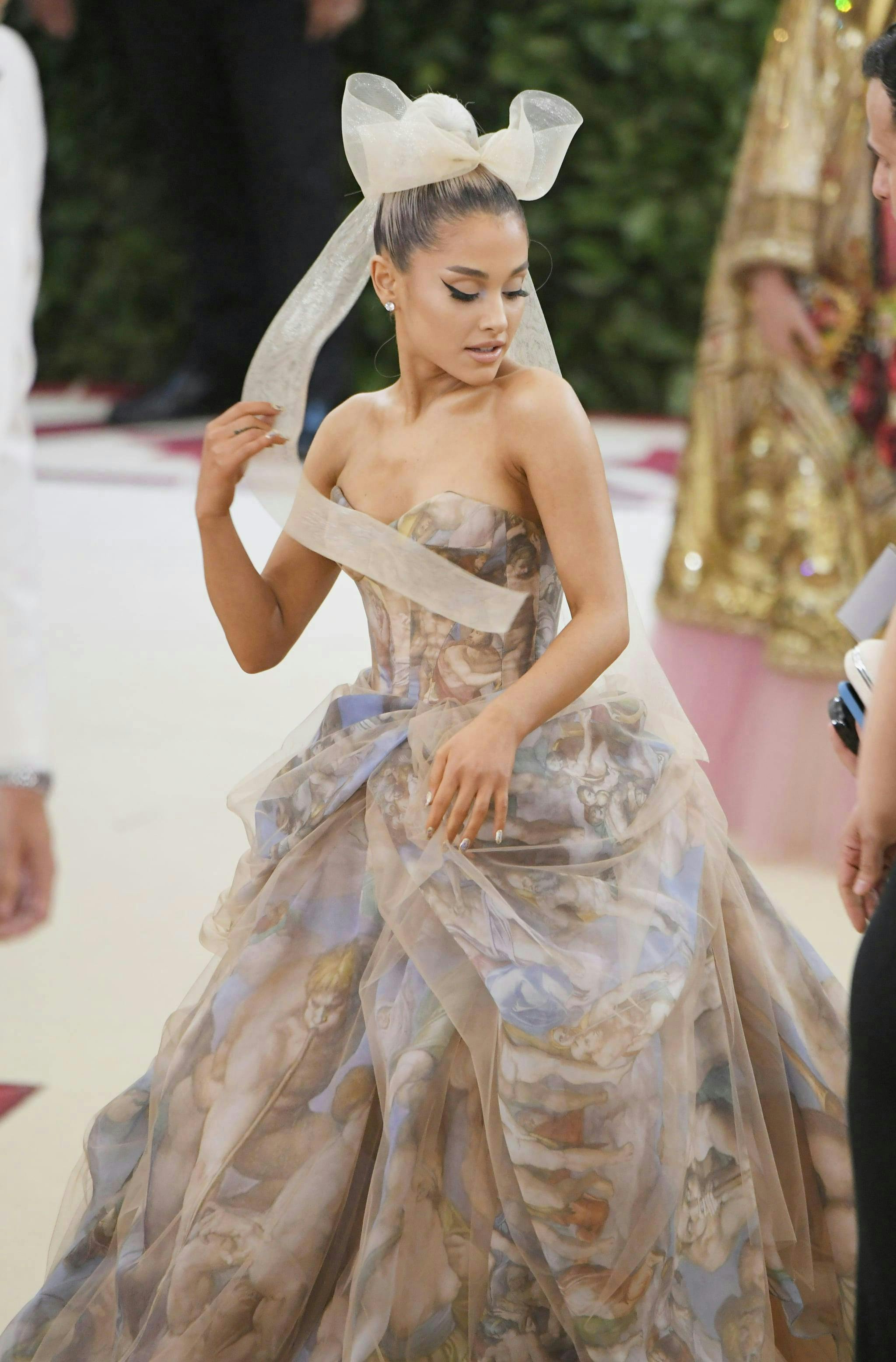 Ariana Grande in a nude gown and large hair bow.