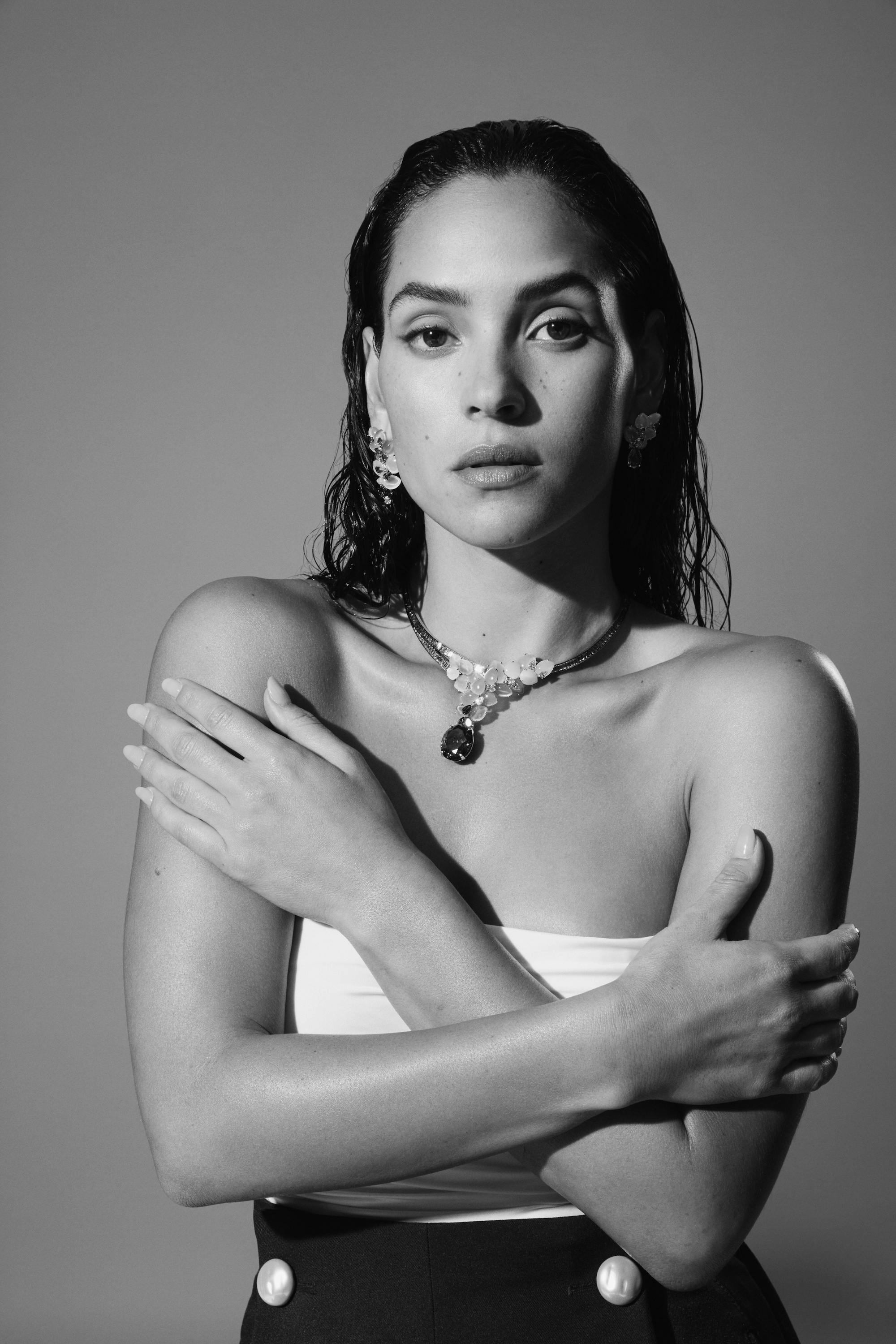 black and white image of adria arjona wearing a white tube top and statement necklace