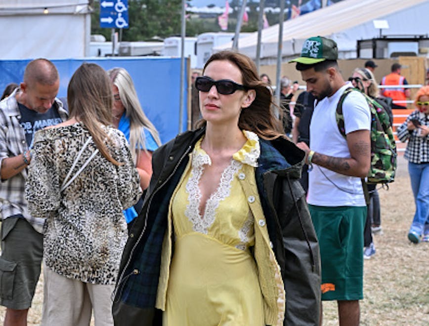 Alexa Chung is spotted at Glastonbury festival teasing her upcoming AW24 Barbour collection in a yellow dress and black jacket. Getty Images.