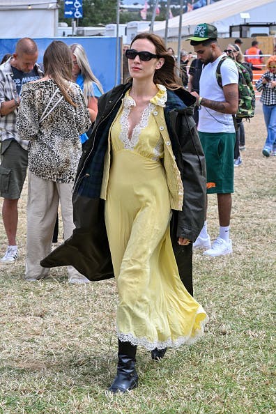 Alexa Chung is spotted at Glastonbury festival teasing her upcoming AW24 Barbour collection in a yellow dress and black jacket. Getty Images.